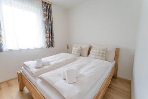 a large white bed with two white towels on it at Apartments Oasis Wörthersee neu & zentral in Krumpendorf am Wörthersee