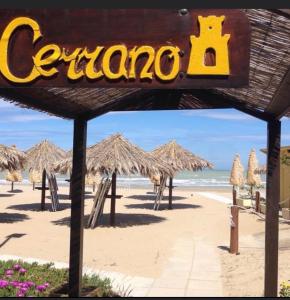 a sign on a beach with some straw umbrellas at Hotel Cerrano in Silvi Marina