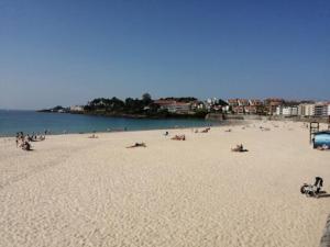 una playa con mucha gente tirada en la arena en Desconectaengalicia Cesteiros, piscina, 100m Playa Silgar, en Sanxenxo