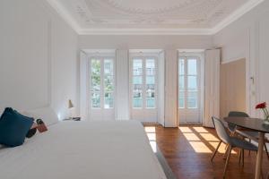 a white bedroom with a bed and a table and chairs at Almada Villa in Almada