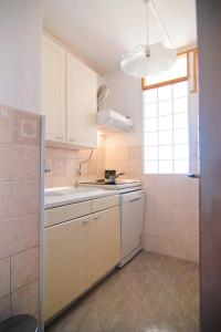 eine Küche mit weißen Schränken, einem Waschbecken und einem Fenster in der Unterkunft Apartment Todorović - Macan in Pula