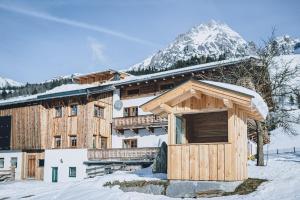 a large wooden building with snow on top of it at Appartement Adamhof Spielberg in Leogang