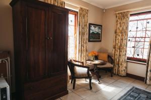 a dining room with a table and a wooden cabinet at Mitre's Edge Pool House in Klapmuts