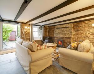 a living room with two couches and a stone fireplace at Dane Cottage in Port Isaac