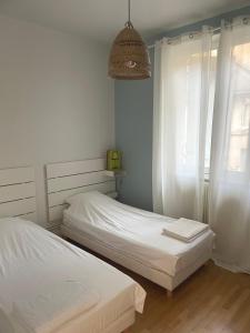 a bedroom with two beds and a pendant light at La Maison Blatin - 2 chambres & parking in Clermont-Ferrand
