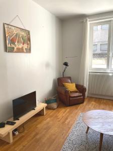 a living room with a television and a chair and a table at La Maison Blatin in Clermont-Ferrand