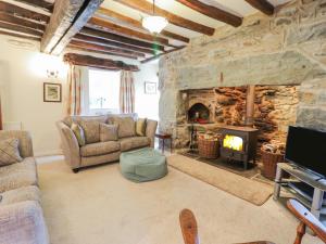 a living room with a stone fireplace and a couch at Ty Glan Yr Afon in Dolgellau