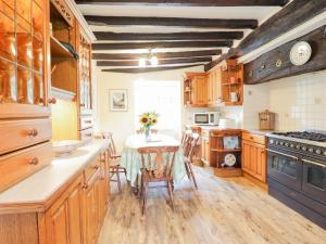 a kitchen with wooden cabinets and a table with chairs at Ty Glan Yr Afon in Dolgellau