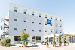 an office building with tables and chairs in front of it at Hotel Ibis Budget Lyon Eurexpo - in Chassieu