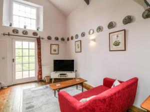 a living room with two red chairs and a tv at Wisteria Cottage in Paignton