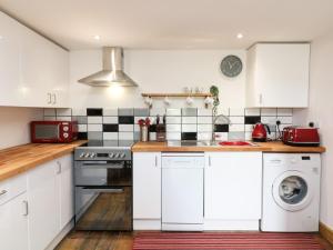 a kitchen with white cabinets and a washer and dryer at Wisteria Cottage in Paignton +11 photos