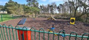 een kleine speeltuin met een hek naast een park bij The Cove in Scarborough