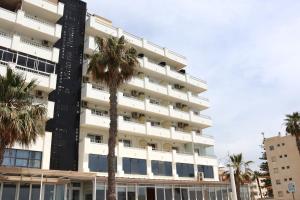 a tall white building with palm trees in front of it at FAY Victoria Beach in Rincón de la Victoria