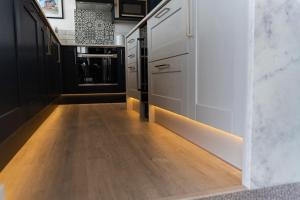 a hallway with a wooden floor and a kitchen with white cabinets at No.1 The Prom in Westward Ho