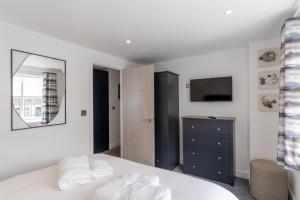 a bedroom with a bed and a dresser and a television at No.1 The Prom in Westward Ho