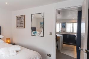 a bedroom with a bed and a mirror and a kitchen at No.1 The Prom in Westward Ho
