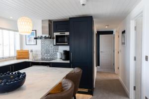 a kitchen with black cabinets and a table with chairs at No.1 The Prom in Westward Ho