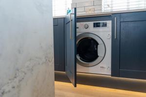 a washing machine in a kitchen with blue cabinets at No.1 The Prom in Westward Ho
