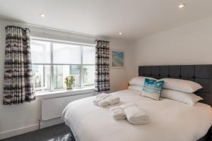 a bedroom with a large white bed with towels on it at No.1 The Prom in Westward Ho