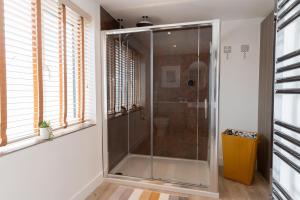 a glass shower stall in a bathroom with windows at No.1 The Prom in Westward Ho