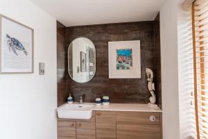 ein Bad mit einem Waschbecken und einem Spiegel in der Unterkunft No.1 The Prom in Westward Ho