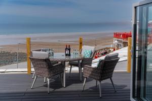 a table and chairs on a deck with the beach at No.1 The Prom in Westward Ho