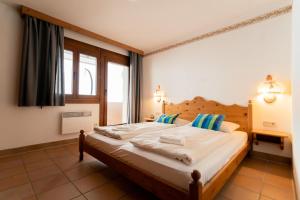 sypialnia z dużym łóżkiem z białą pościelą i niebieskimi poduszkami w obiekcie Apartment Weitblick - Almresort Gerlitzen w mieście Treffen am Ossiacher See