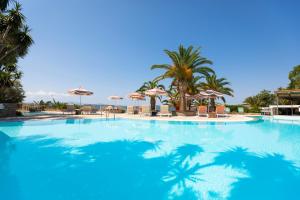 a large swimming pool with palm trees and umbrellas at Eagles Palace in Ouranoupoli
