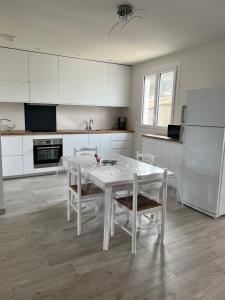 biała kuchnia z białym stołem i krzesłami w obiekcie le Rocher w mieście La Plaine-sur-Mer