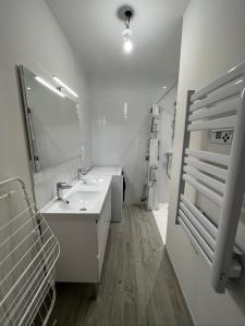 a white bathroom with a sink and a mirror at le Rocher in La Plaine-sur-Mer