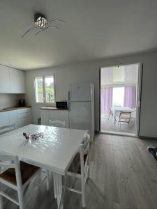 biała kuchnia z białym stołem i krzesłami w obiekcie le Rocher w mieście La Plaine-sur-Mer