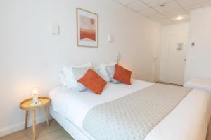 1 dormitorio con 1 cama blanca con almohadas de color naranja y azul en Hôtel Porte Mars - Reims Gare Centre Arena, en Reims