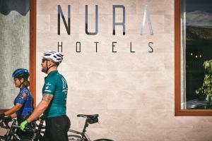 two people riding bikes in front of a hotel at Nura Santa Ponsa & Spa in Santa Ponsa