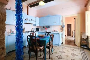 een keuken met blauwe kasten en een tafel met stoelen bij Casa vacanza Soletina a Soleto cuore del Salento in Soleto