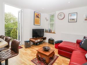 un soggiorno con divano rosso e tavolo di Apartment 4 10 Somers Court a Paignton