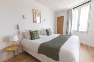 a white bedroom with a large bed and a window at Hôtel Porte Mars - Reims Gare Centre Arena in Reims