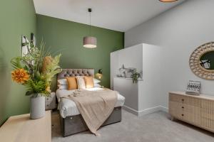 a bedroom with a bed and a green wall at Fen Lane Lodge in Snetterton