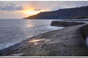 a sunset over a body of water with the ocean at Large property which is all about location, location , location ! Lovely Comfortable 2 bedroom flat which is spacious and one of the best value properties of this size so close to the sea , beaches and restaurants 1 min to the sea ! in Lyme Regis