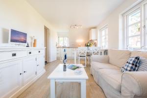 ein weißes Wohnzimmer mit einer Couch und einem Tisch in der Unterkunft Haderslebener Str 28 in Westerland