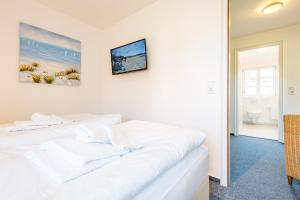 ein weißes Bett in einem Zimmer mit Bad in der Unterkunft Haderslebener Str 28 in Westerland