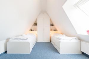 2 Betten in einem Schlafzimmer im Dachgeschoss mit weißen Möbeln in der Unterkunft Haderslebener Str 28 in Westerland