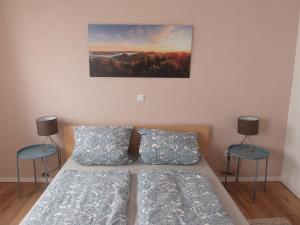 een slaapkamer met een bed met 2 stoelen en een schilderij aan de muur bij Ferienwohnung Palatina Annweiler in Annweiler am Trifels