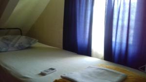 a bed with a remote control on it next to a window at Dusica in Vrnjačka Banja