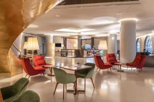 a lobby with red chairs and tables and a kitchen at Grand Hotel Açores Atlântico in Ponta Delgada