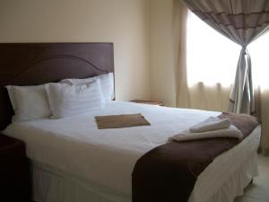 a bedroom with a large white bed with a window at The Gibeon Ville Self-Catering in Gaborone