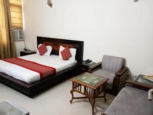a bedroom with a bed and a chair and a table at Hotel Home Stay Dwarka in New Delhi