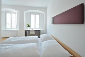 a white bedroom with two beds and a desk at Hotel zum Goldenen Schiff in Enns