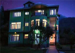 een groot groen gebouw met 's nachts verlichting bij Calm Holiday Inn in Srinagar