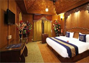a bedroom with a bed and a television and flowers at Calm Holiday Inn in Srinagar