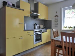 une cuisine avec des armoires jaunes et une table en bois dans l'établissement Ferienwohnung G11 "Idyll", à Graal-Müritz
